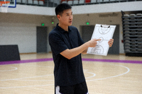 篮球教练在场边指挥战术，手持战术板讲解阵型